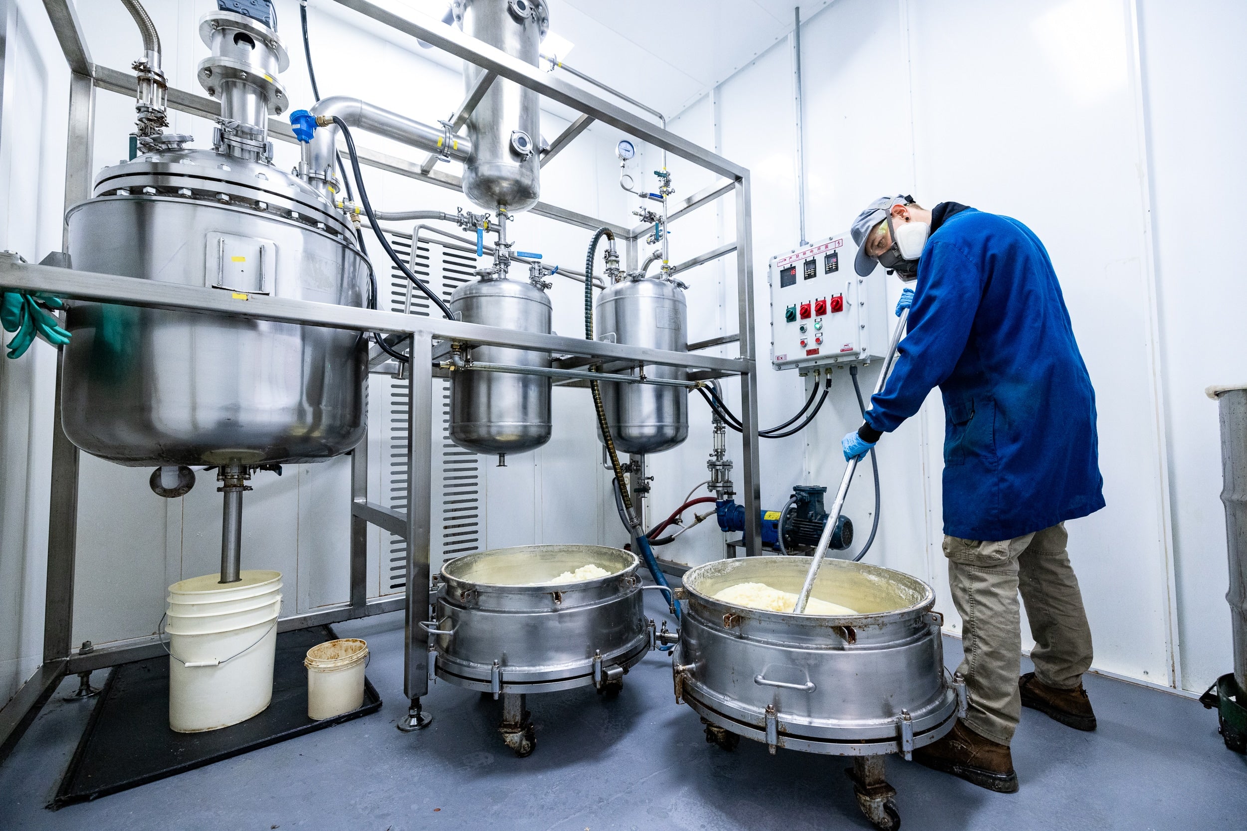A man in a blue coat is diligently working on a machine, showcasing his expertise in a mechanical environment.
