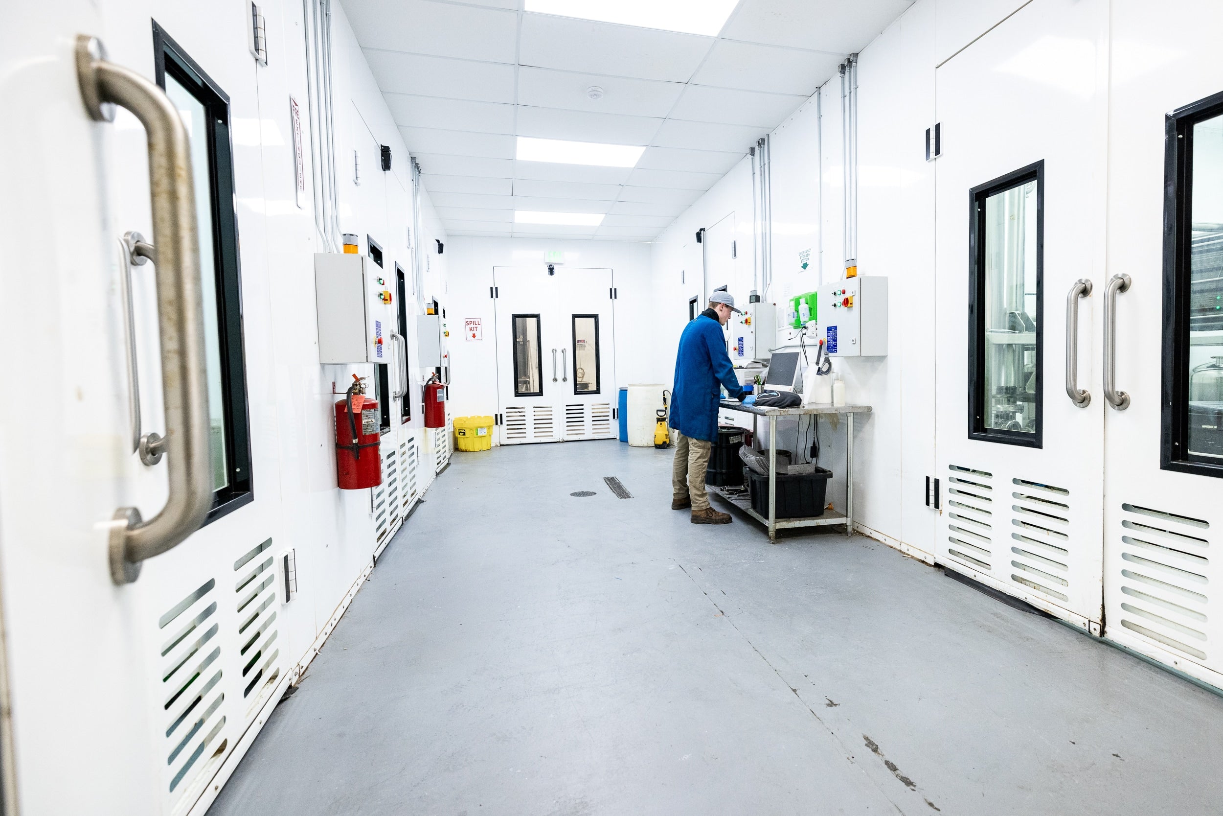 A man in a lab is focused on operating a complex machine, surrounded by scientific equipment and tools.