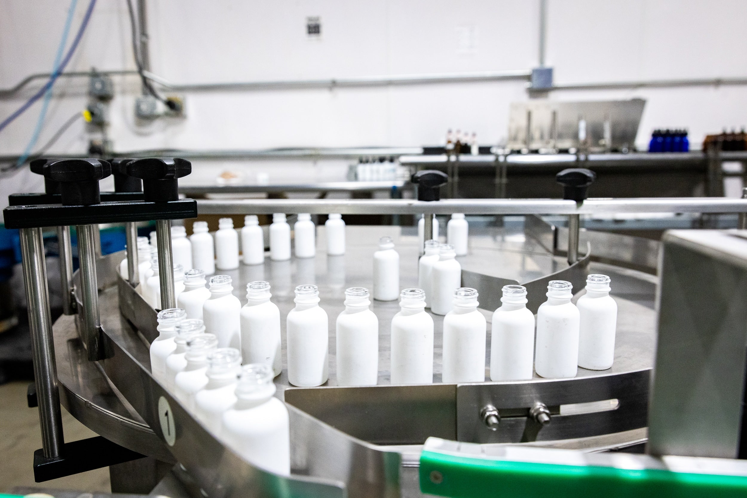 A line of bottles moving along a conveyor belt in a factory setting, showcasing the production process.