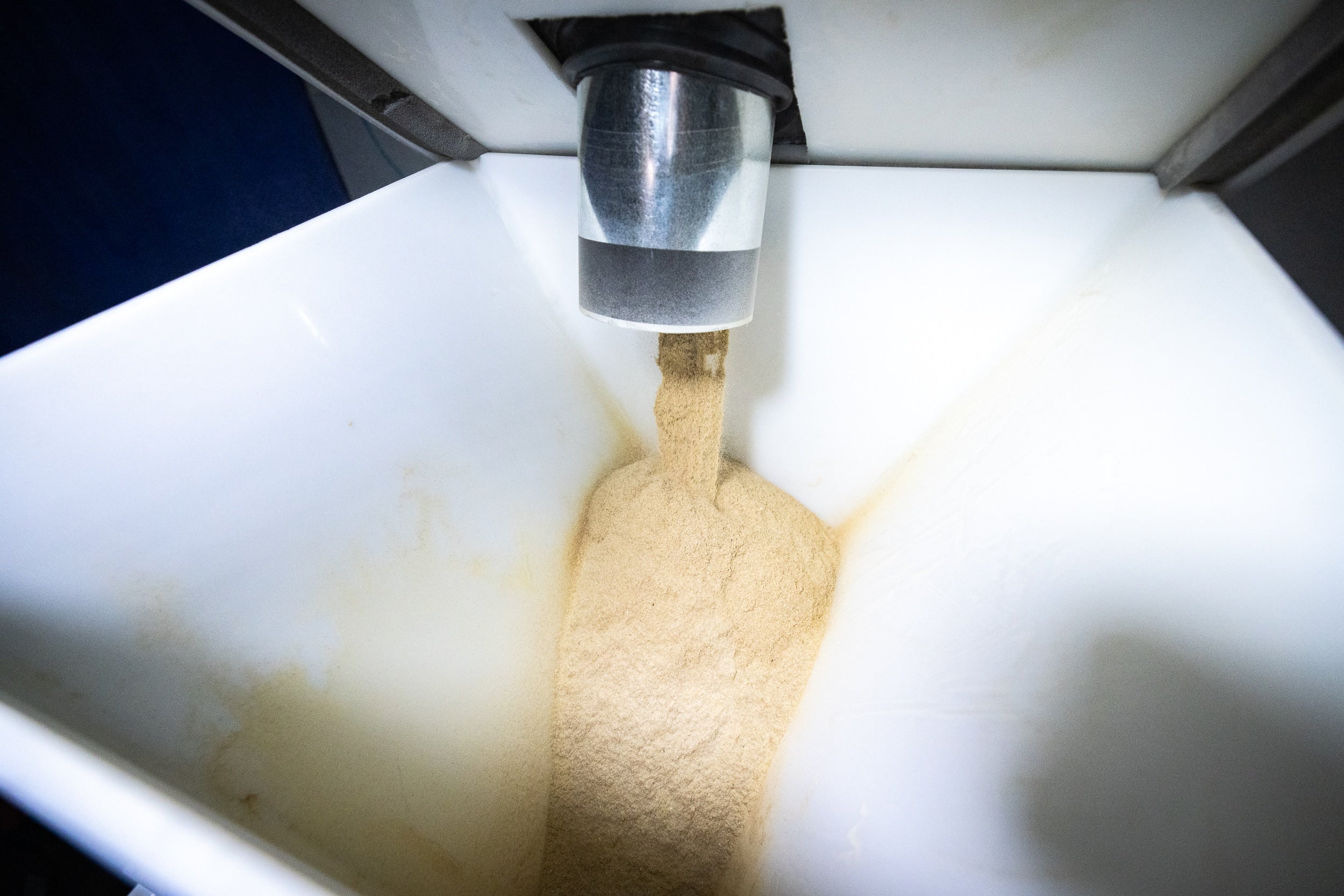 A machine is actively processing powder in a container, illustrating the automated mixing process.